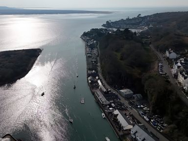 A coastal harbor with boats docked along the waterfront and buildings lining the shore at Fisherman Cove in Porthmadog