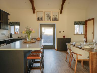 A kitchen with an island counter and stools and a dining table with chairs at Cuddfan in Llanfwrog near Bodedern