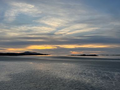 A beach with wet sand and a sunset sky with clouds at Cuddfan in Llanfwrog near Bodedern