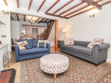 A living room with two sofas one blue and one gray and a round patterned ottoman at Chestnut Cottage in Wetwang near Great Driffield