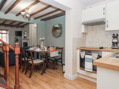 A kitchen and dining area with a wooden table set for a meal and an oven with a towel at Chestnut Cottage in Wetwang near Great Driffield