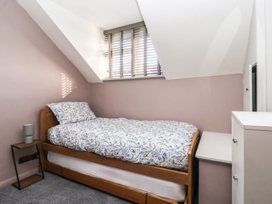 A bedroom with a single bed floral bedding a side table with a lamp and a white chest of drawers at Chestnut Cottage in Wetwang near Great Driffield