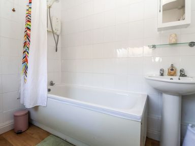 A bathroom with a bathtub shower white shower curtain and a pedestal sink at Chestnut Cottage Wetwang near Great Driffield