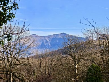 A mountain landscape with leafless trees in the foreground and a clear blue sky at Dowlais Llanllyfni near Penygroes