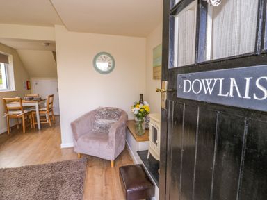 An open black door showing a living area with a single armchair and a dining table in the background at Dowlais in Llanllyfni near Penygroes