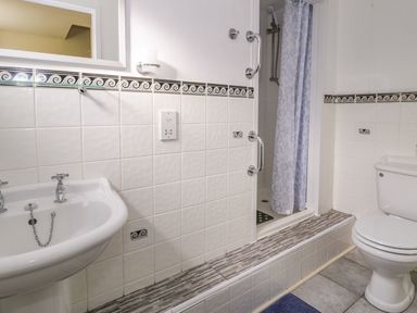 A bathroom with a sink toilet and shower with a blue curtain at Dowlais in Llanllyfni near Penygroes