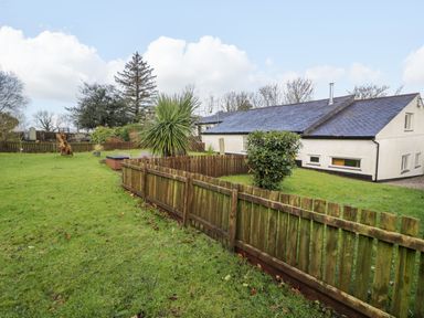 A house with a fenced garden with grass and plants under a blue sky at Dowlais in Llanllyfni near Penygroes