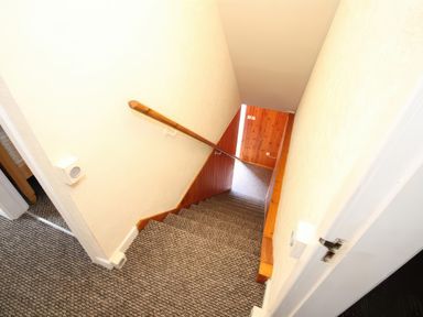 A carpeted staircase with a wooden handrail and white walls at Igamogam in Llanllyfni near Penygroes