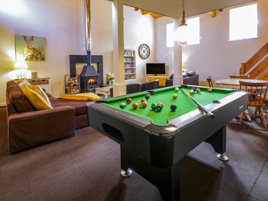 A living room with a pool table sofa a wood burning stove TV and a dining table at Igamogam in Llanllyfni near Penygroes