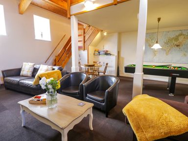 A living area with leather sofa and chairs coffee table with flowers round dining table pool table and stairs at Igamogam Llanllyfni near Penygroes