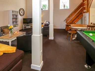 A living room with a pool table wooden dining table with chairs and a staircase at Igamogam in Llanllyfni near Penygroes