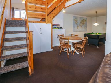 A game room with a staircase round table with chairs and a pool table at Igamogam in Llanllyfni near Penygroes