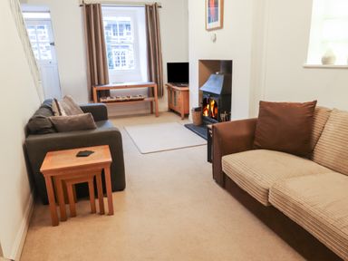 A living room with two sofas a fireplace a wooden table and a small television at Ty Glyn in Beddgelert