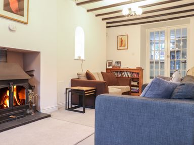 A living room with a fireplace two sofas a wooden bookshelf and glass double doors at Ty Glyn in Beddgelert