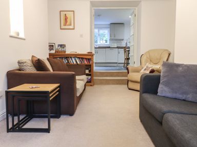 A living room with two sofas an armchair a bookshelf and nesting tables at Ty Glyn in Beddgelert