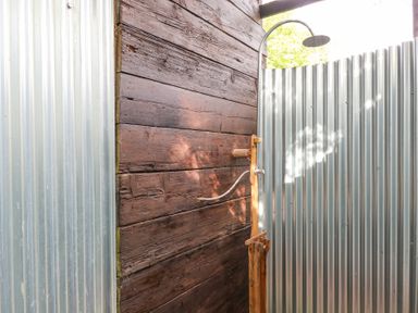 An outdoor shower with a wooden wall and corrugated metal panels at Brandon House Farm Yurt Brandon Parva near Mattishall