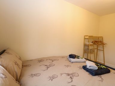 A bedroom with a bed with animal print bedding and a wooden clothes rack with hangers at Rabbit Warren Lodge in Snettisham