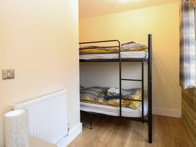 A bedroom with a black metal bunk bed and folded towels near a window at Rabbit Warren Lodge in Snettisham
