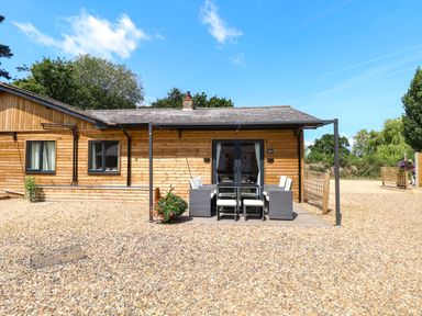 An outdoor patio area with a dining table and chairs at Rabbit Warren Lodge in Snettisham