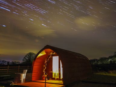 A glamping pod with light inside and stars in the night sky at Ty Twt Teifi in Tregaron