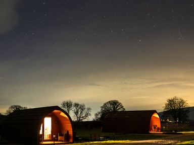 Two cabins with light at night at Ty Twt Teifi in Tregaron