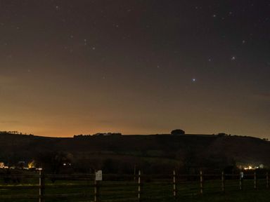 A view of stars and hills with lights at Ty Twt Teifi in Tregaron