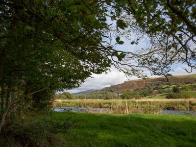 A landscape view featuring trees and a river with hills in the background at Ty Twt Teifi Tregaron