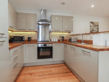 A kitchen with grey cabinets wooden countertops and stainless steel appliances at 1 Miller's Island near Lanreath