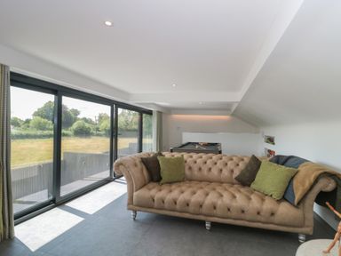 A living room with a sofa and large windows at Number 7 in Bishop Sutton