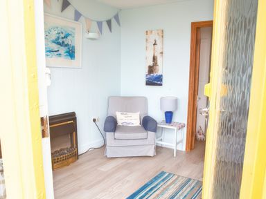 A small sitting area with an armchair a side table with a lamp a fireplace and wall art at Homestead Aberdesach near Penygroes