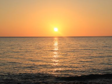 A sunset over the ocean with the sun reflecting on the water at Homestead in Aberdesach near Penygroes