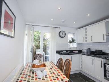 A kitchen with dining table chairs countertop appliances and glass doors at Quarrymans cottage in Beddgelert