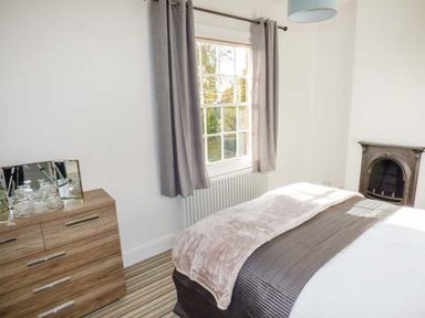 A bedroom with a bed near a window and a wooden dresser with mirrors at 1 Willow Cottage in Upton Upon Severn