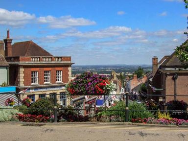 A street view with brick buildings shops and hanging flower baskets at 1 Willow Cottage in Upton Upon Severn