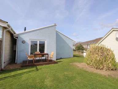 A backyard with a wooden deck with a table and chairs by a blue house at Pierpont D1 Norton near Yarmouth