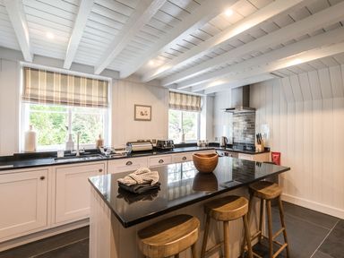 A kitchen with a black countertop island and wooden stools at Tan Llan in Llanelltyd near Dolgellau