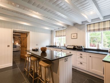 A kitchen with a black countertop island and wooden stools at Tan Llan in Llanelltyd near Dolgellau