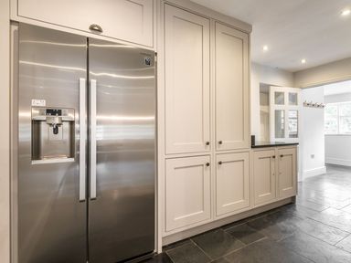 A kitchen with a stainless steel refrigerator and white cabinetry on a tiled floor at Tan Llan in Llanelltyd near Dolgellau