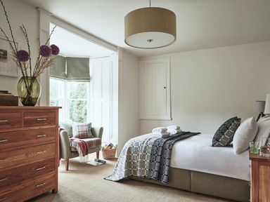 A bedroom with a bed folded towels and a chair by the window at Tan Llan in Llanelltyd near Dolgellau