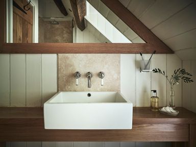 A bathroom sink with wall-mounted taps a mirror and toiletries at Tan Llan in Llanelltyd near Dolgellau