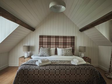 A bedroom with a bed with patterned pillows and blankets and bedside tables with lamps at Tan Llan in Llanelltyd near Dolgellau