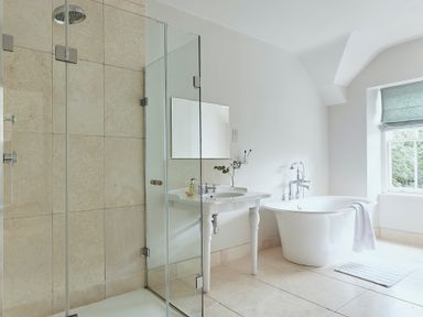 A bathroom with a glass shower enclosure sink with taps flower vase freestanding bathtub and window at Tan Llan in Llanelltyd near Dolgellau
