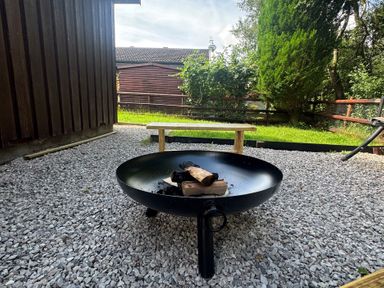 An outdoor area with a fire pit and wooden bench at Fig Tree Lodge Hutton Roof near Penrith