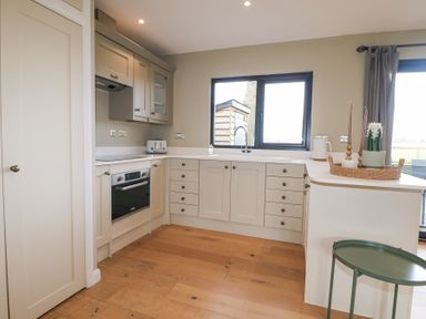 A kitchen with cabinets oven toaster and a window at Holm Oaks Cottage in Busbridge near Godalming