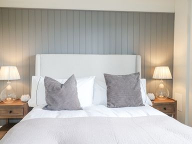 A bedroom with a bed with gray and white pillows and two bedside tables with lamps at Holm Oaks Cottage in Busbridge near Godalming