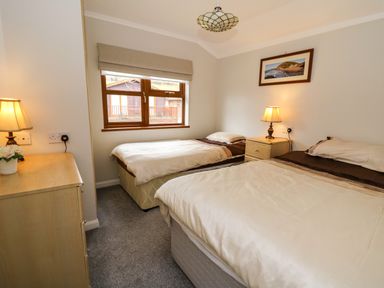 A bedroom with two single beds a chest of drawers and a window at 2 Riverside Lodge Abercych near Cenarth