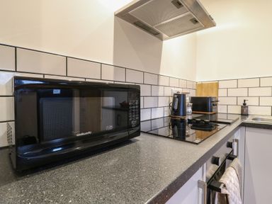 A kitchen countertop with a microwave kettle toaster stove and oven at Hub House Three Oaks near Hastings