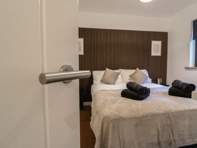 A bedroom with a bed covered in beige blanket and black towels on top at Hub House in Three Oaks near Hastings