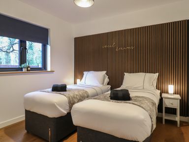A bedroom with two single beds a wooden slatted headboard and a window at Hub House in Three Oaks near Hastings