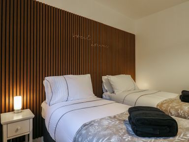 A bedroom with two single beds and a nightstand with a lamp at Hub House in Three Oaks near Hastings
